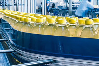 Yellow beverage bottles moving on blue conveyor in factory