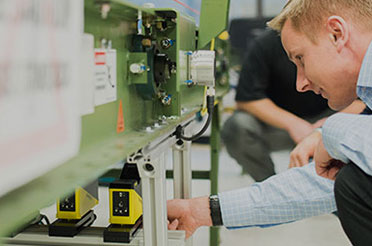 Cognex customer field representative inspecting laser profilers under conveyor